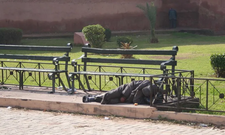 Fotografia d'una persona dormint sota un banc. Imatge de Adam Axon. Llicència d'ús CC BY 2.0