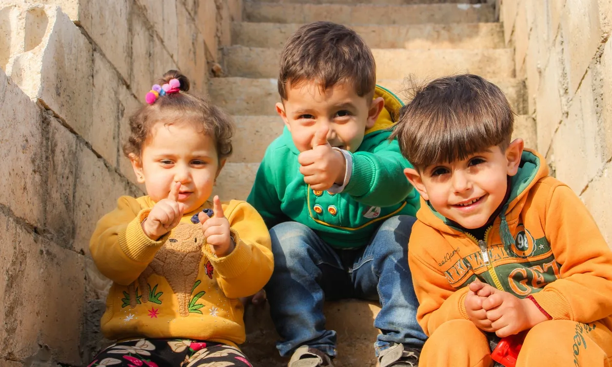 Tres infants asseguts en unes escales