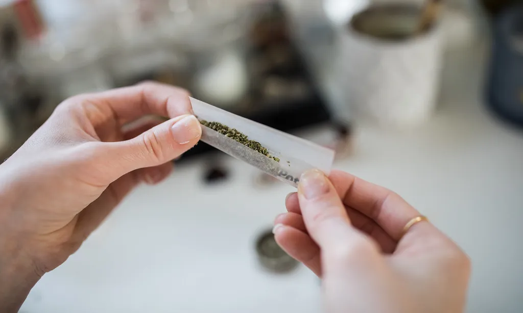 Una persona consumidora de drogues es prepara una cigarreta de cànnabis.