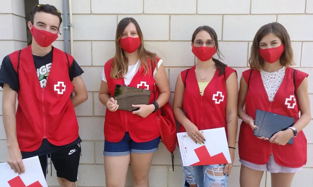 Quatre joves amb les armilles de la Creu Roja