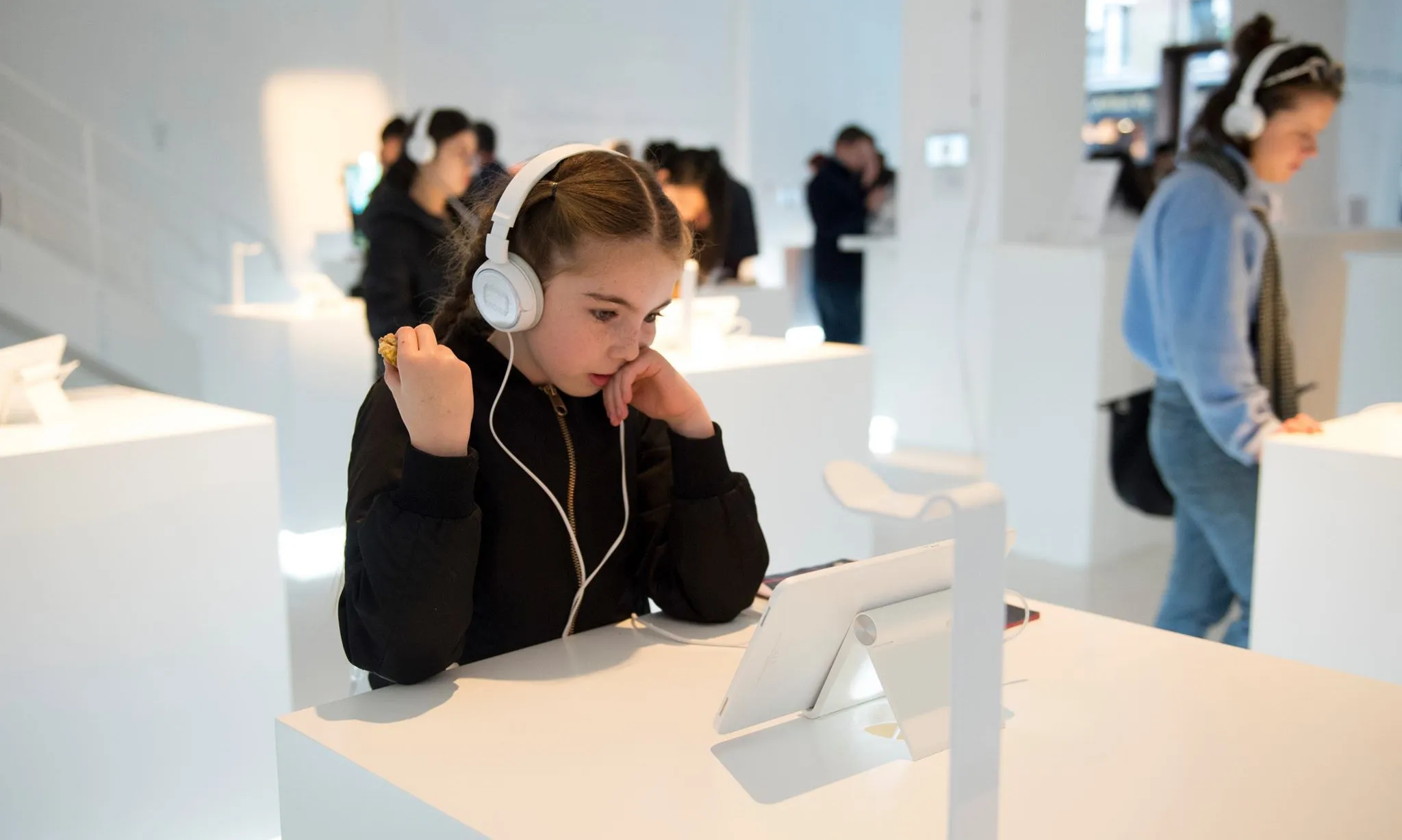 Una nena amb cascos davant una tauleta a l'espai comunitari The Glass Room