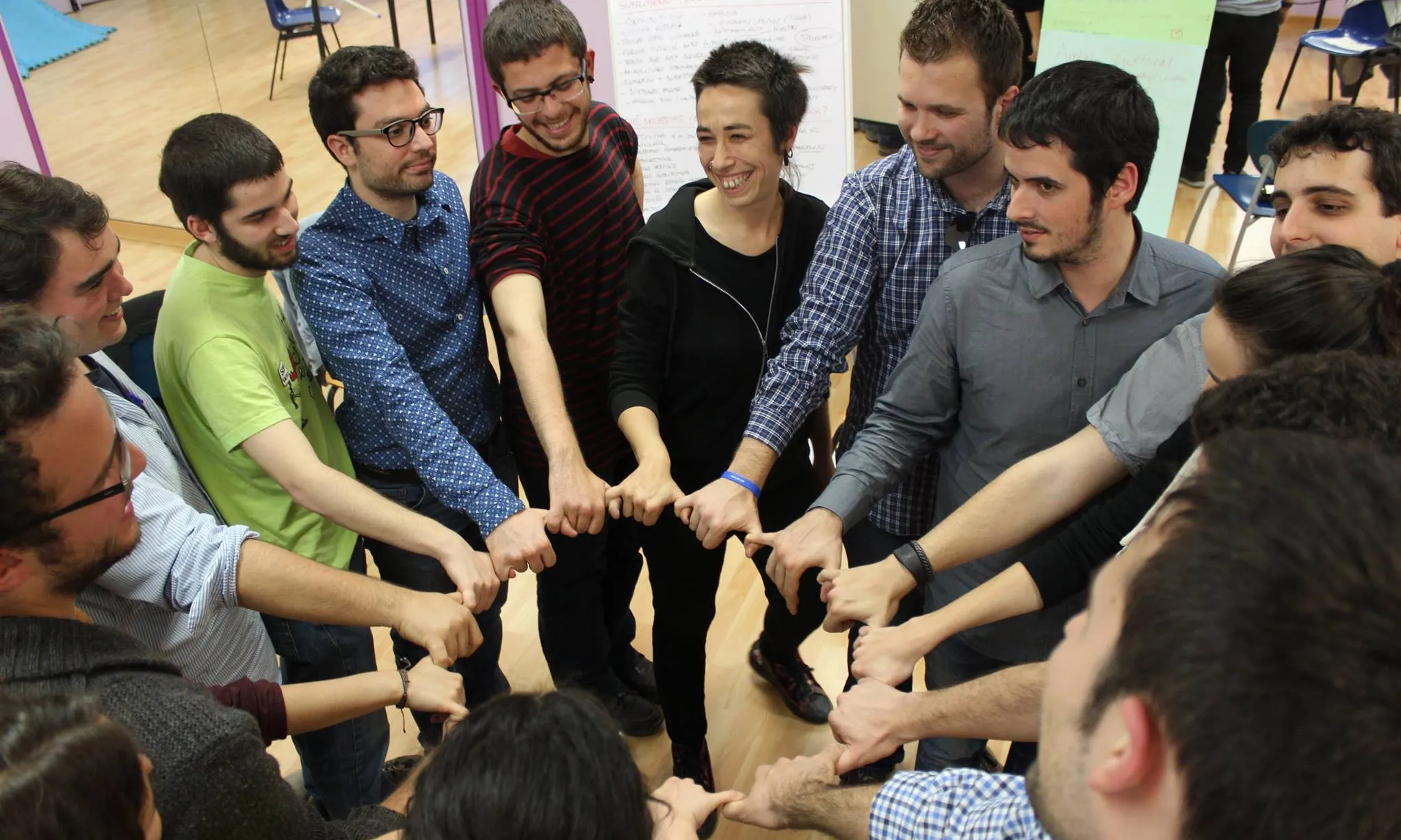 Joves en una rotllana posant les mans al centre en una activitat de la 10a Àgora Jove, posant 