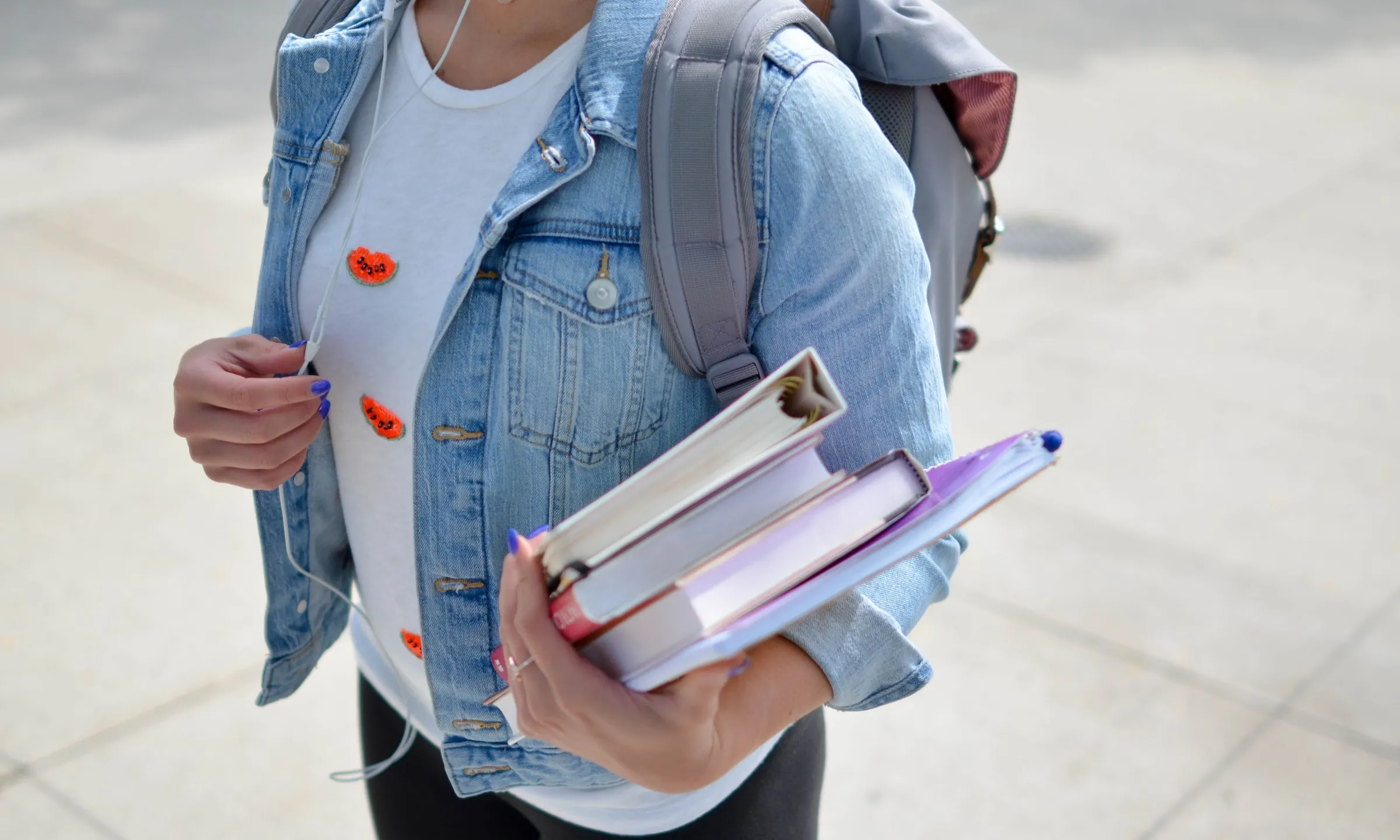 Noia amb uns llibres a la mà i una motxilla a l'esquena
