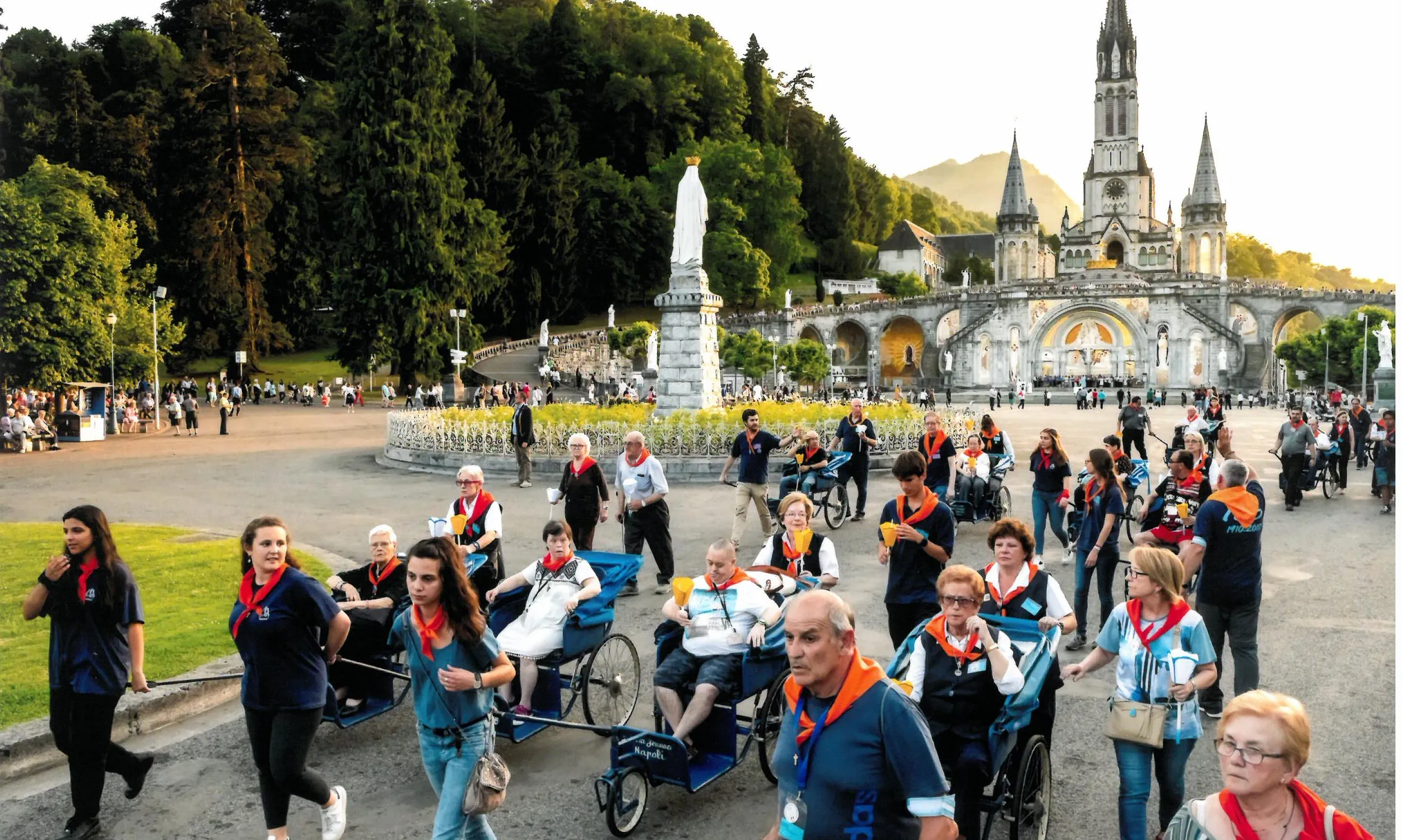 Fotografia on es poden veure diferents voluntaris portant malalts a Lourdes. Imatge de Xavi Ortiz.