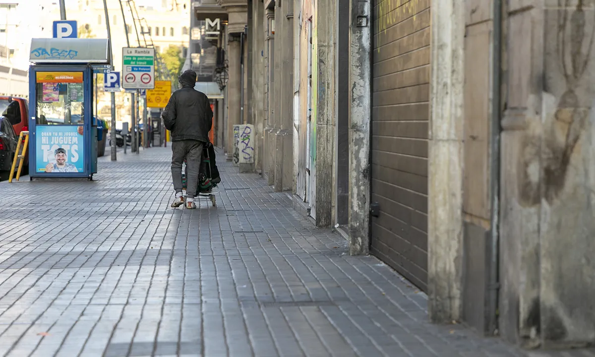 Una persona sense llar camina pels carrers buits de Barcelona durant el confinament.
