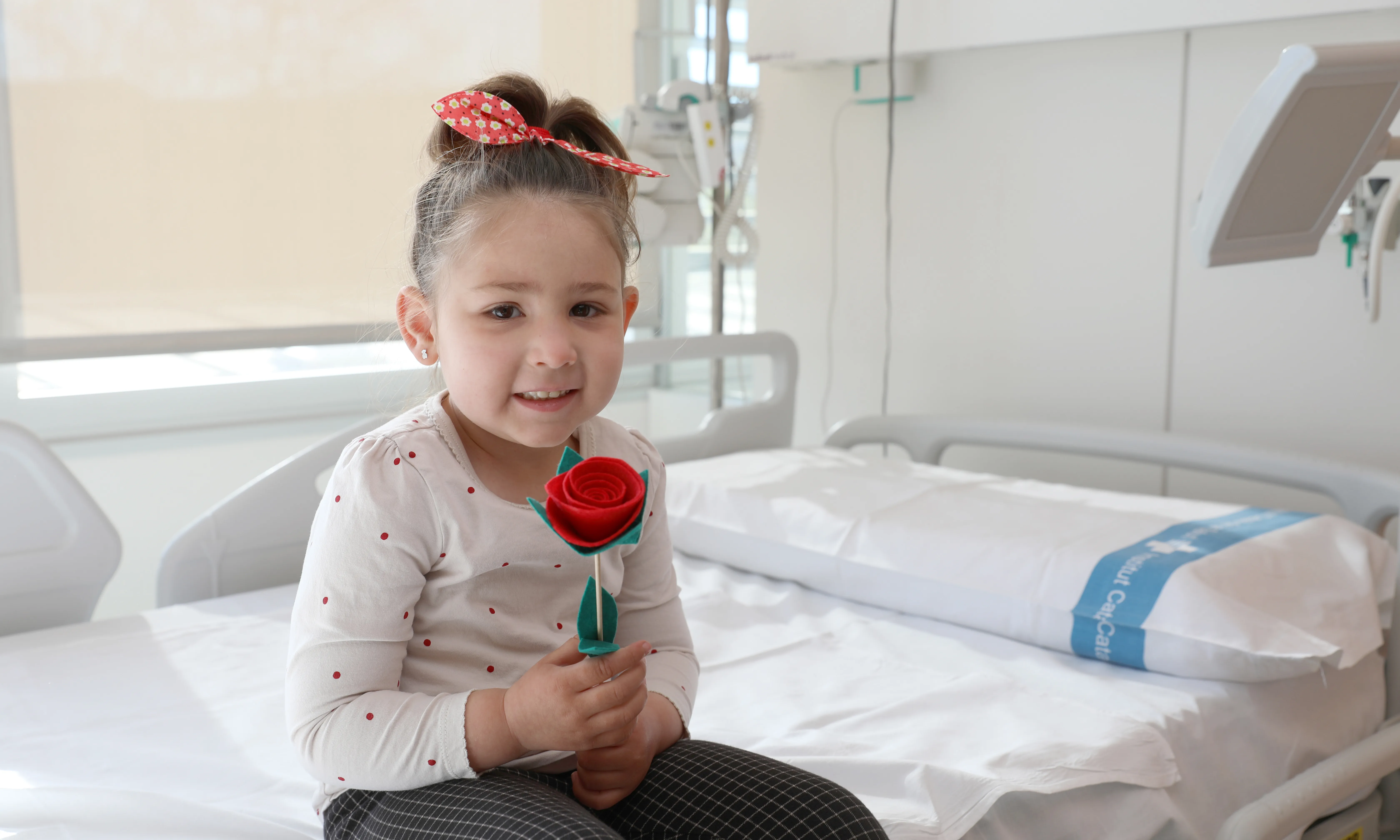 Una de les nenes ingressades a Vall d'Hebron amb la rosa solidària de Sant Jordi.