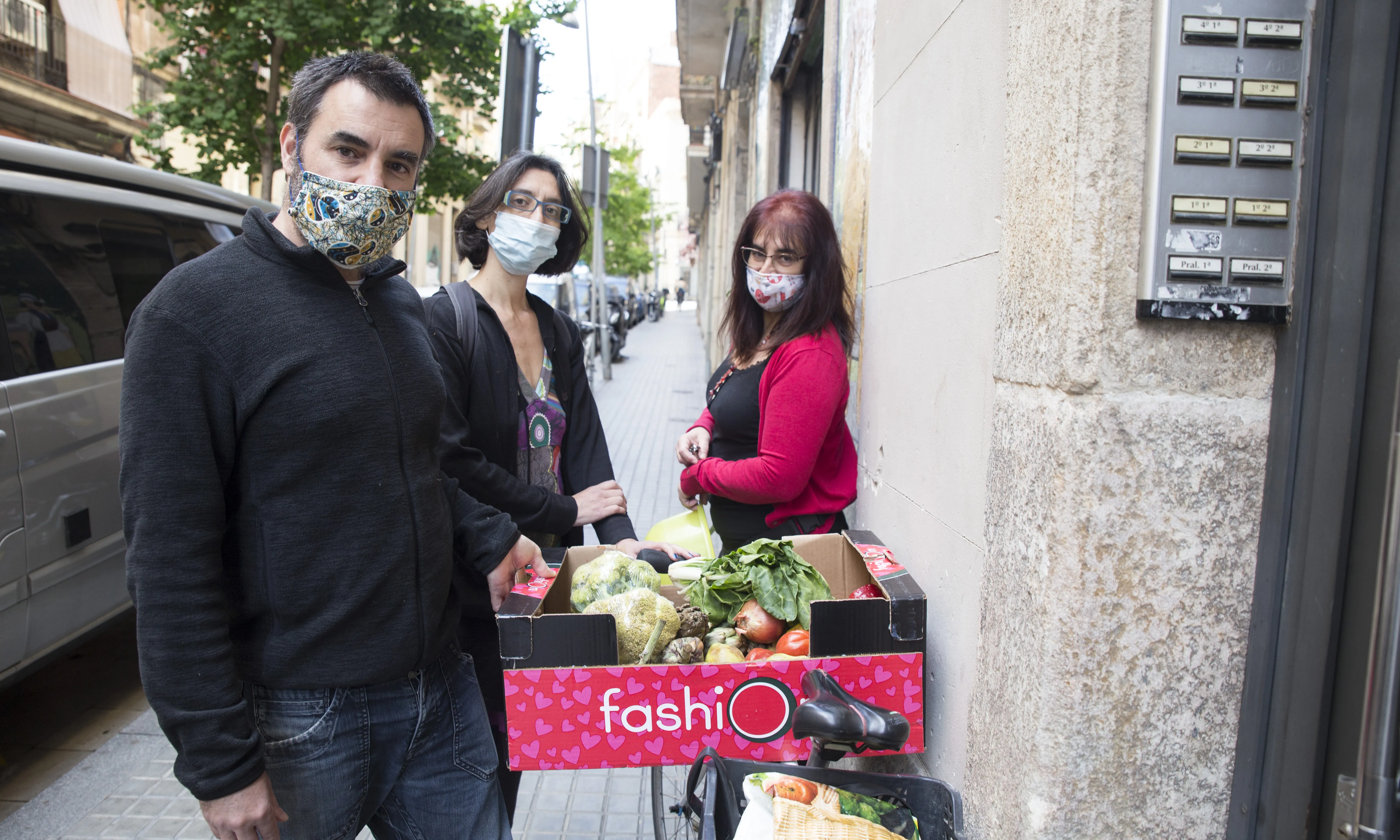 Tres membres del grup de les Espigadores amb la caixa de fruita