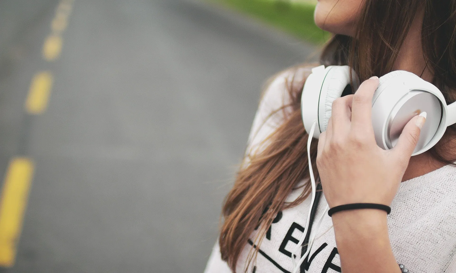 Una noia escolta música mentre camina per una carretera.