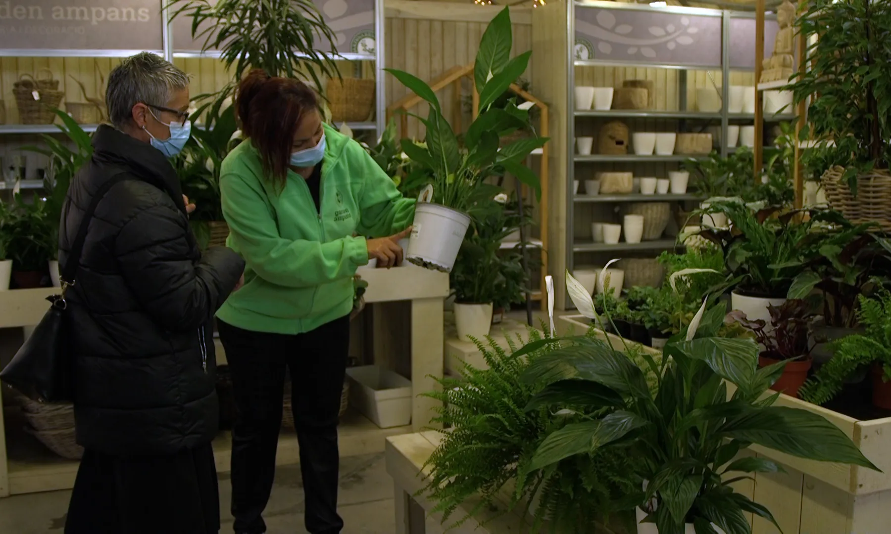 Una clienta sent atesa per una treballadora de la botiga Garden, d'objectes de jardineria i plantes, de la Fundació Ampans