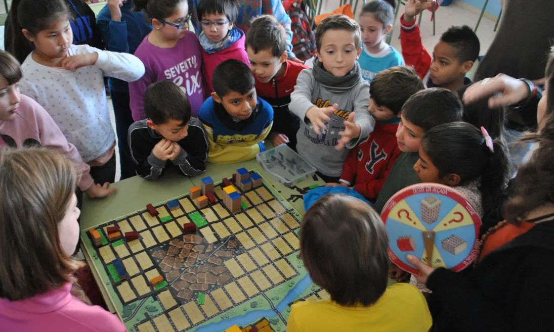 Un grup d'infants participen al taller educatiu de pedagogia urbana, en el qual s'utilitza com a material principal una maqueta d'una ciutat