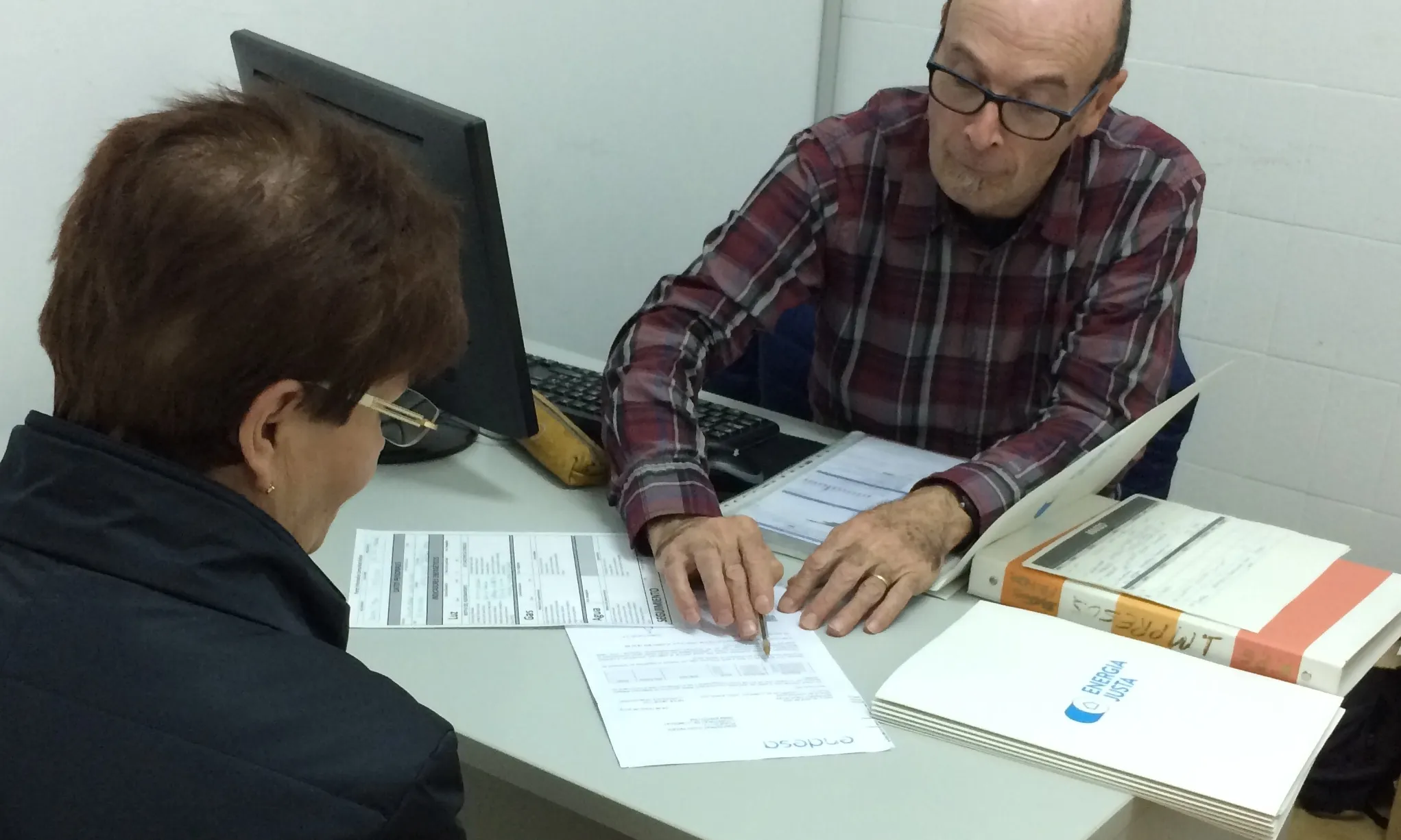 Voluntari amb una persona usuària a un dels punts informatius que té el projecte impulsat per ABD i Ecoserveis.