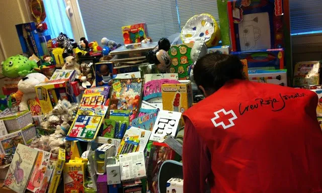Un voluntari de la Creu Roja guardant joguines recollides