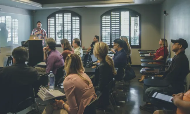 Un grup de persones com a públic d'una classe en representació del seminari 'La Mirada Restaurativa al Món Educatiu'. Font: Llicència CC Unsplash