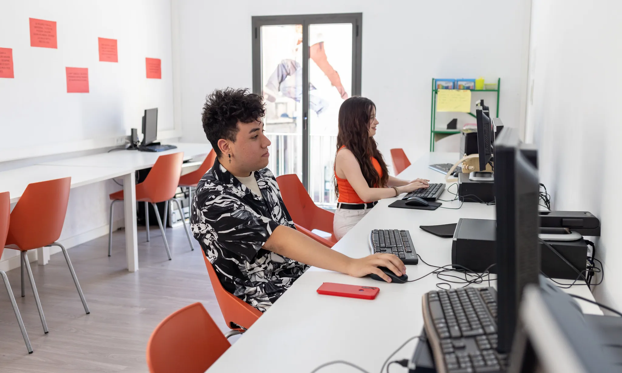 Dues joves en una sala amb ordinadors.