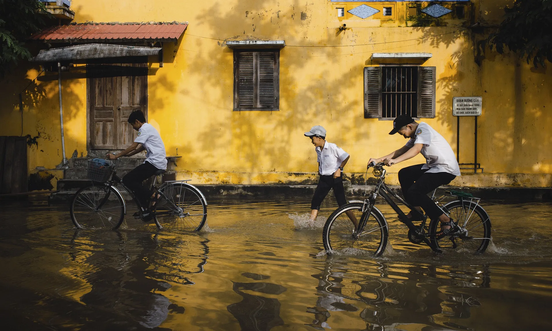 Nens en bicicleta en un carrer inundat per les pluges.