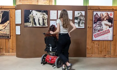 Noies mirant el quadre d'una exposició, una d'ella va en cadira de rodes elèctrica