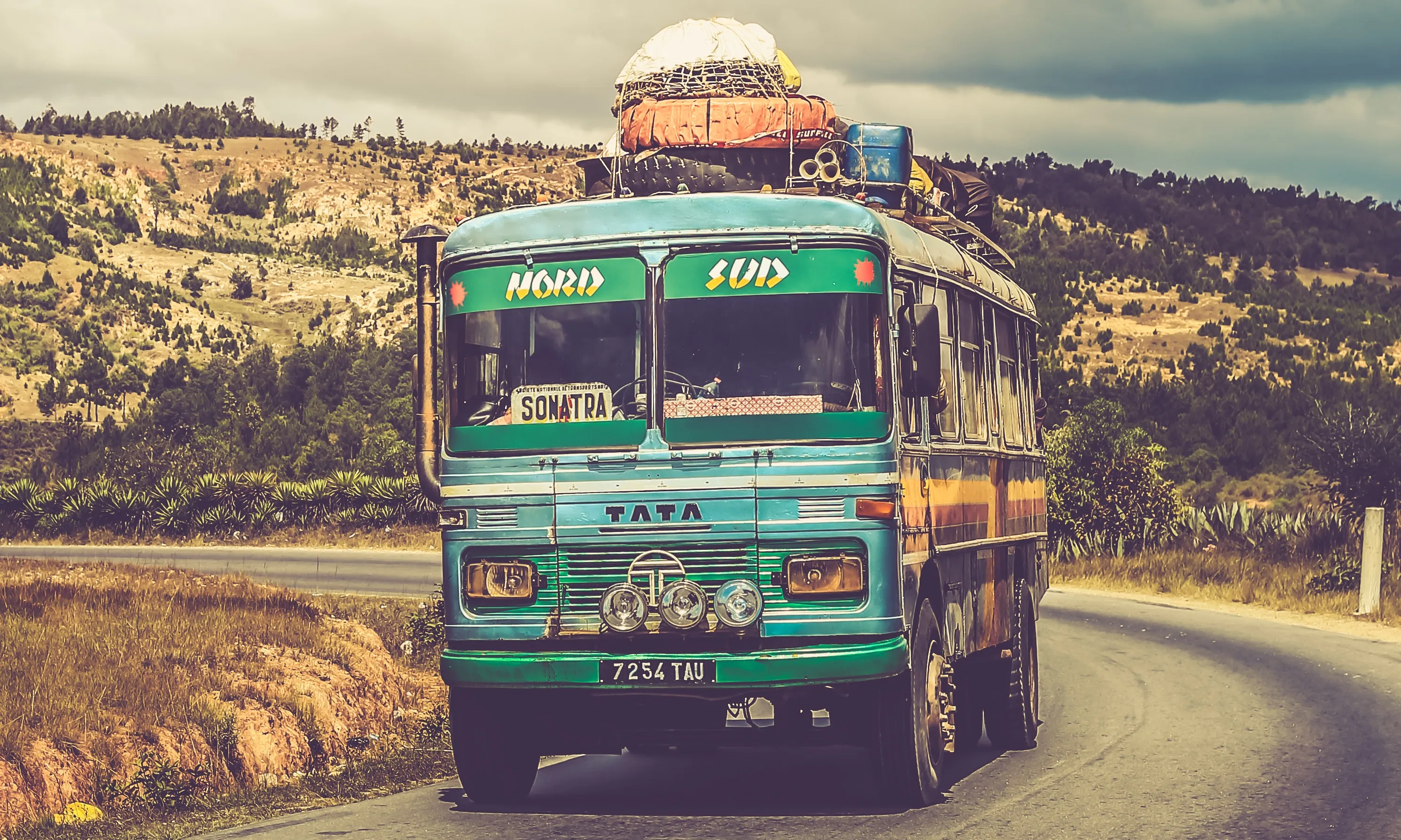 Autocar carregat amb paquets al sostre en una carretera. Font: Pexels - Chut FOTO Autocar carregat amb paquets al sostre en una carretera. Font: Pexels - Chut FOTO