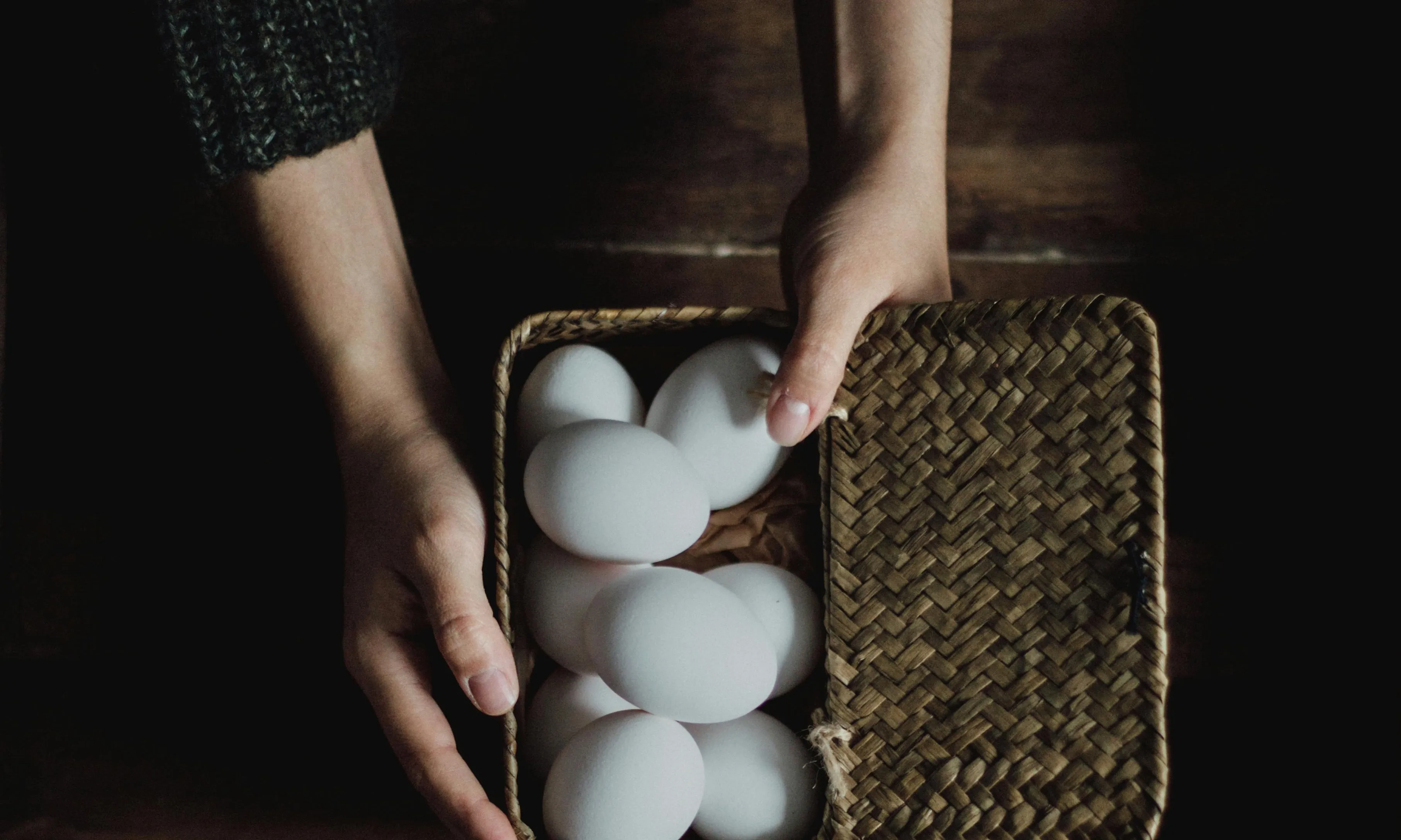 Mans mostrant cistell amb ous blancs. Font: Pexels - Daniela Constantini