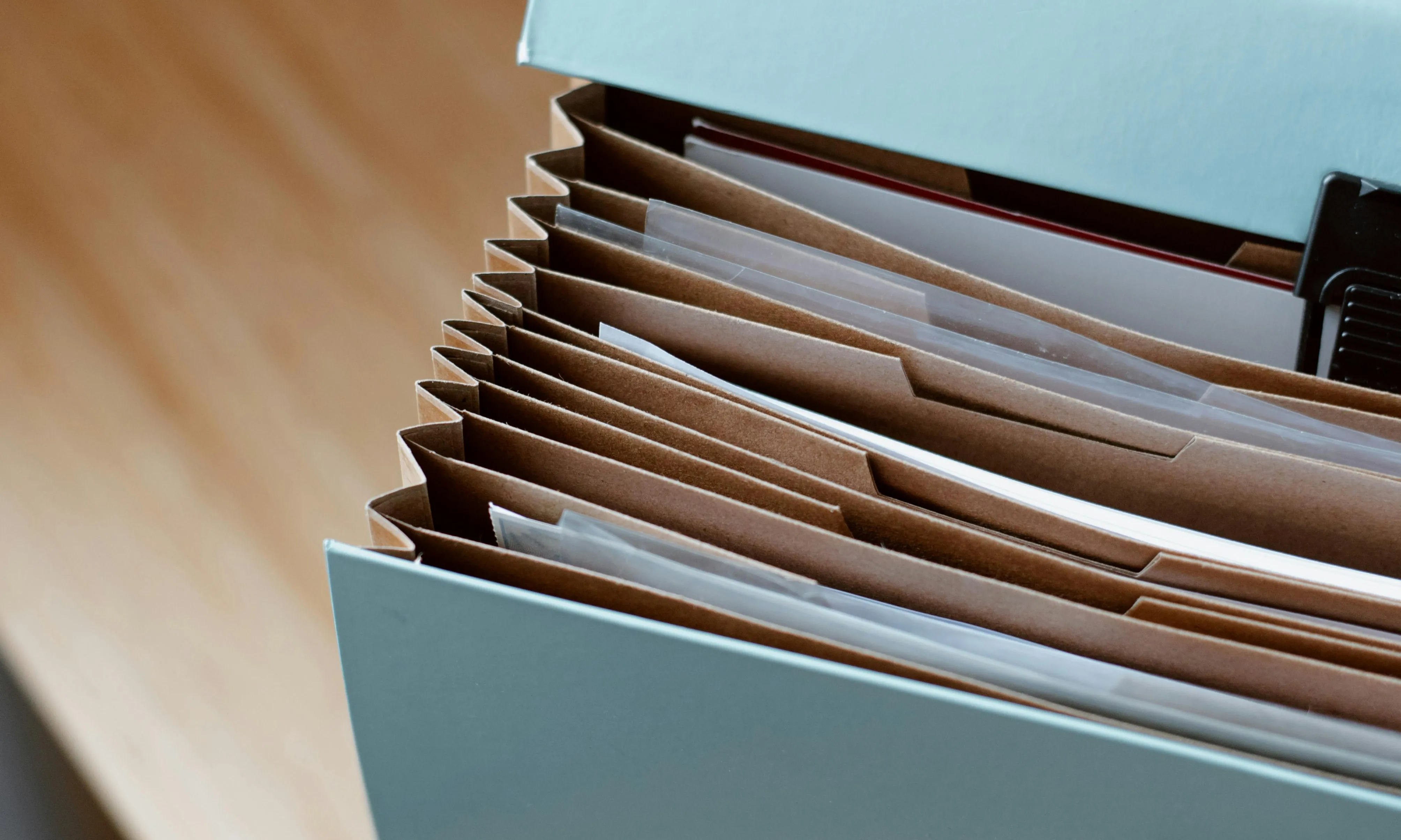 Carpeta arxivadora de papers oberta sobre una taula. Font: Pexels - Anete Lusina