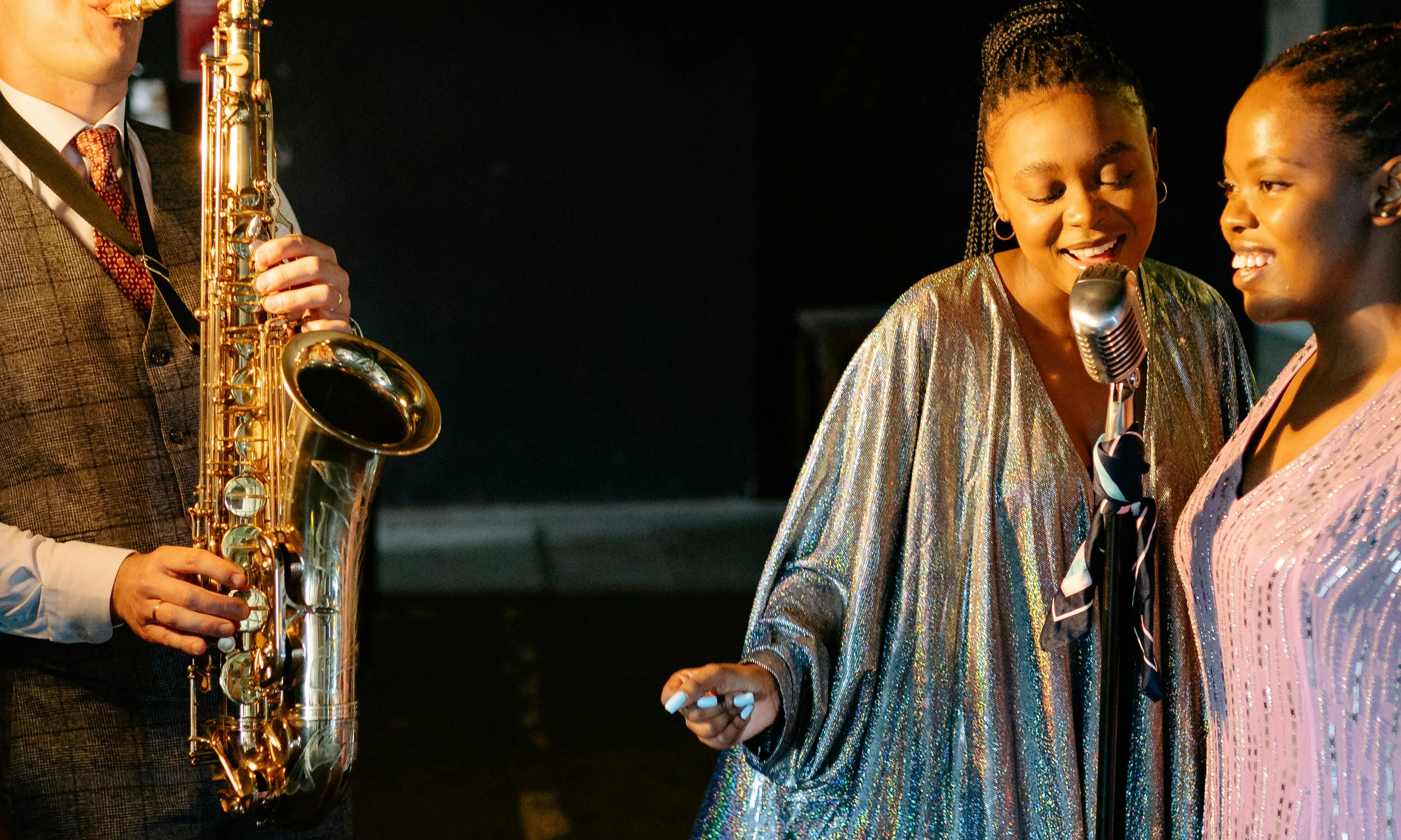 Saxofonista amb cantants de jazz a l'escenari