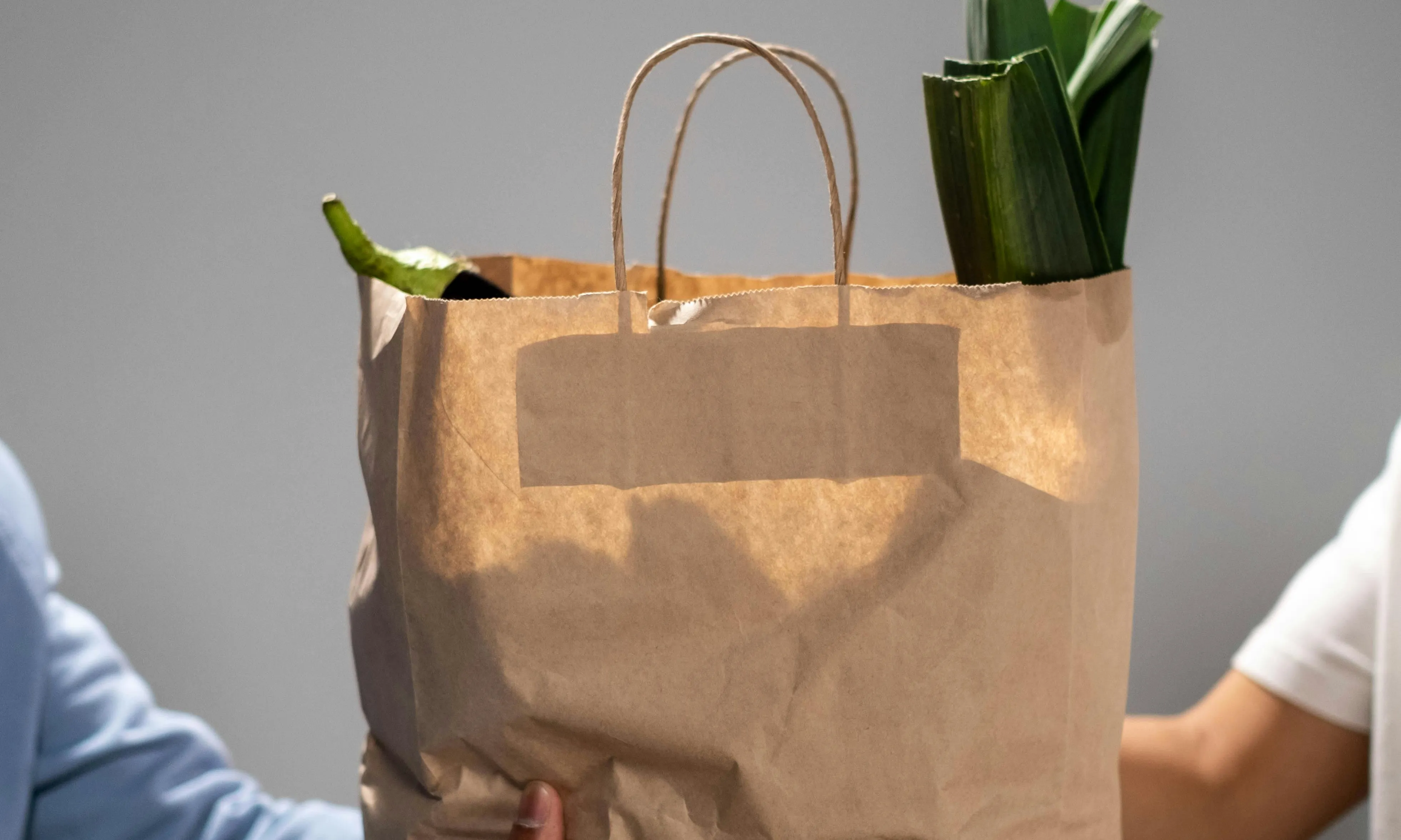 Mans agafant una bossa de paper amb compres a dins Mans agafant una bossa de paper amb compres a dins