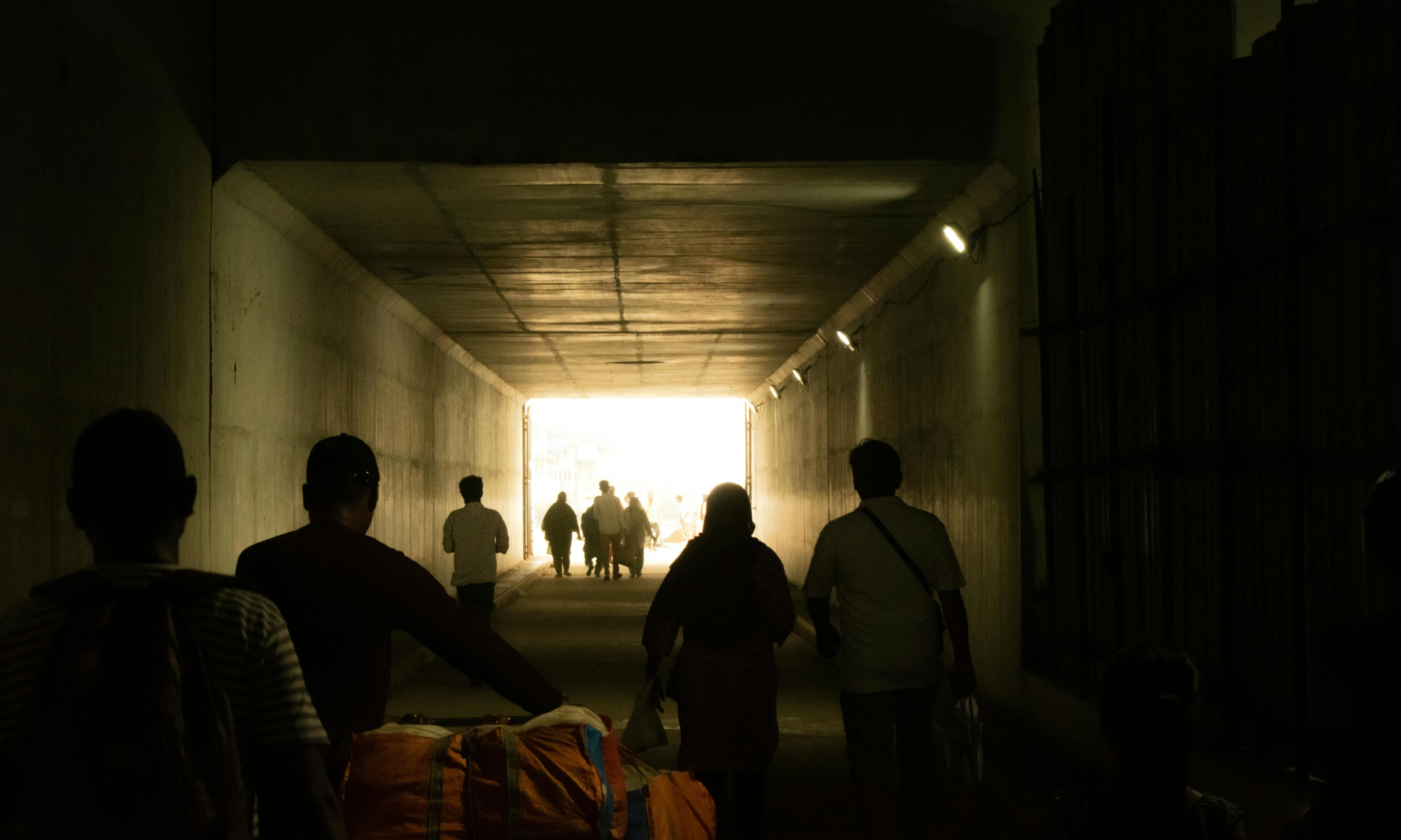 Persones migrants passant per un túnel Persones migrants passant per un túnel