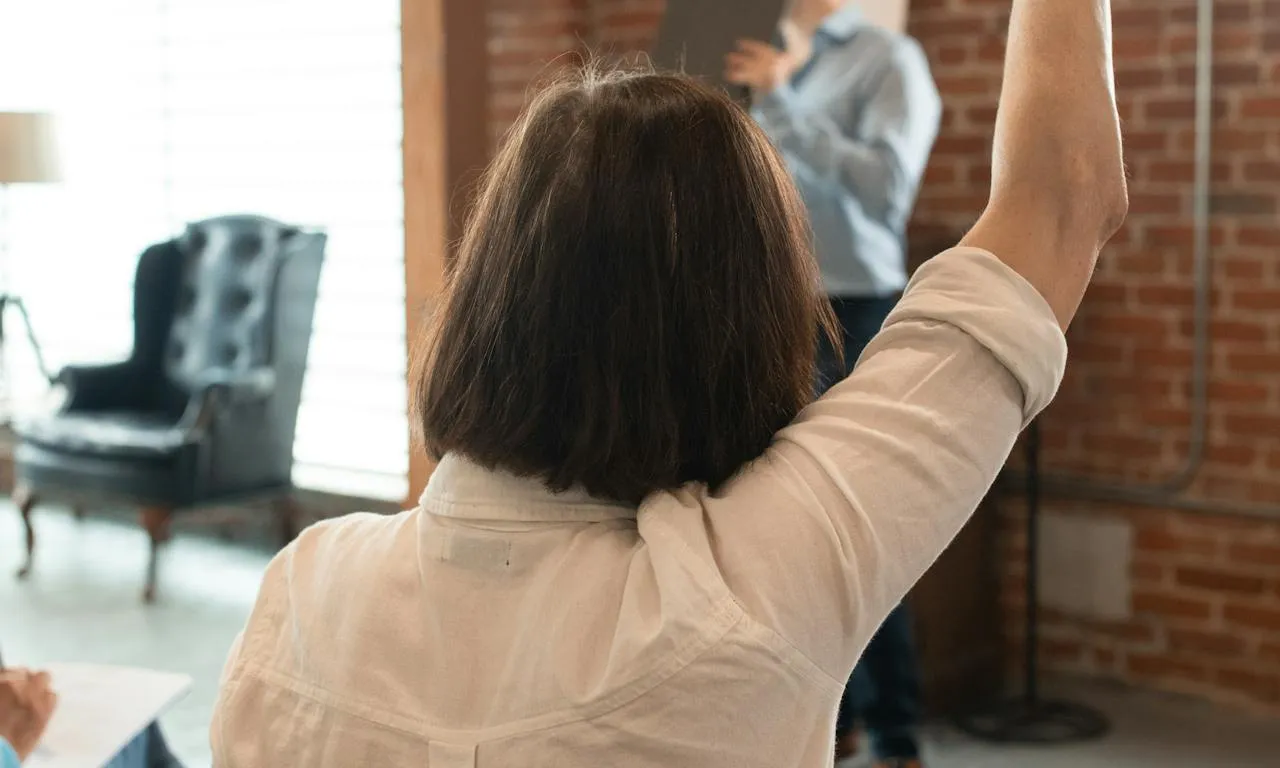 Dona aixecant la mà en una classe