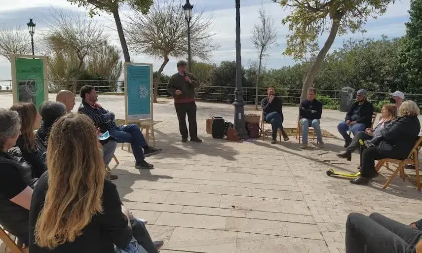 Un grup de persones en rotllana debatent i compartint experiències.