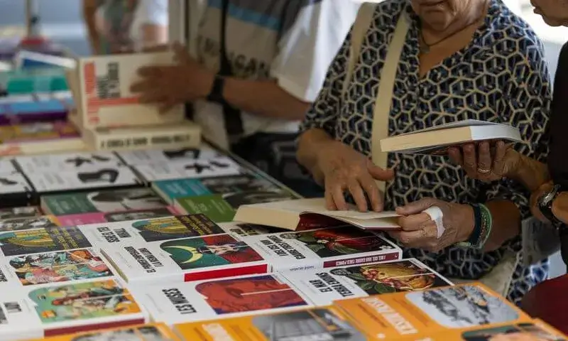 Detall de les mans d’una persona gran fullejant un llibre a la 41a edició de la Setmana del Llibre en Català.