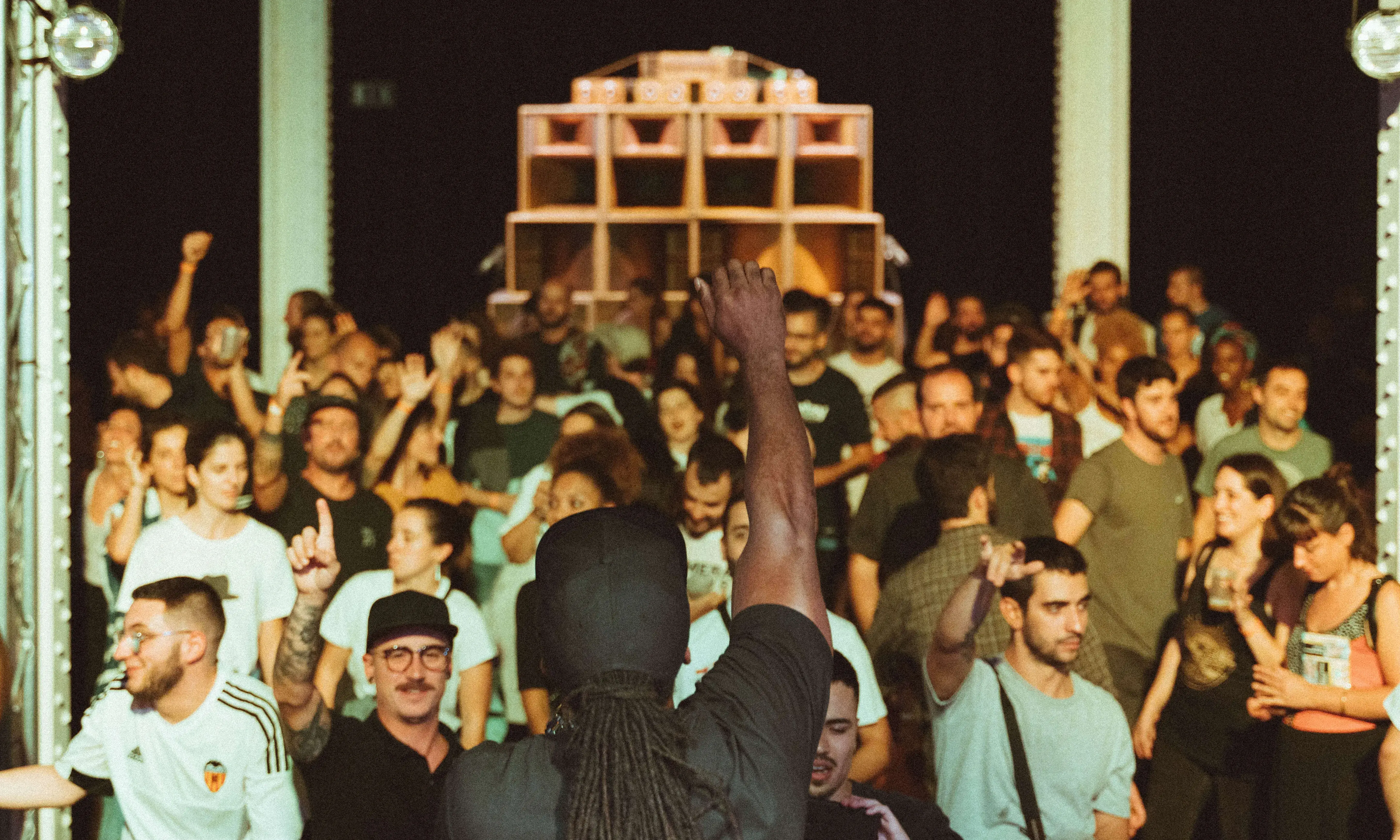 Imatge d'una sala plena de persones ballant amb un artista tocant a dalt de l'escenari.