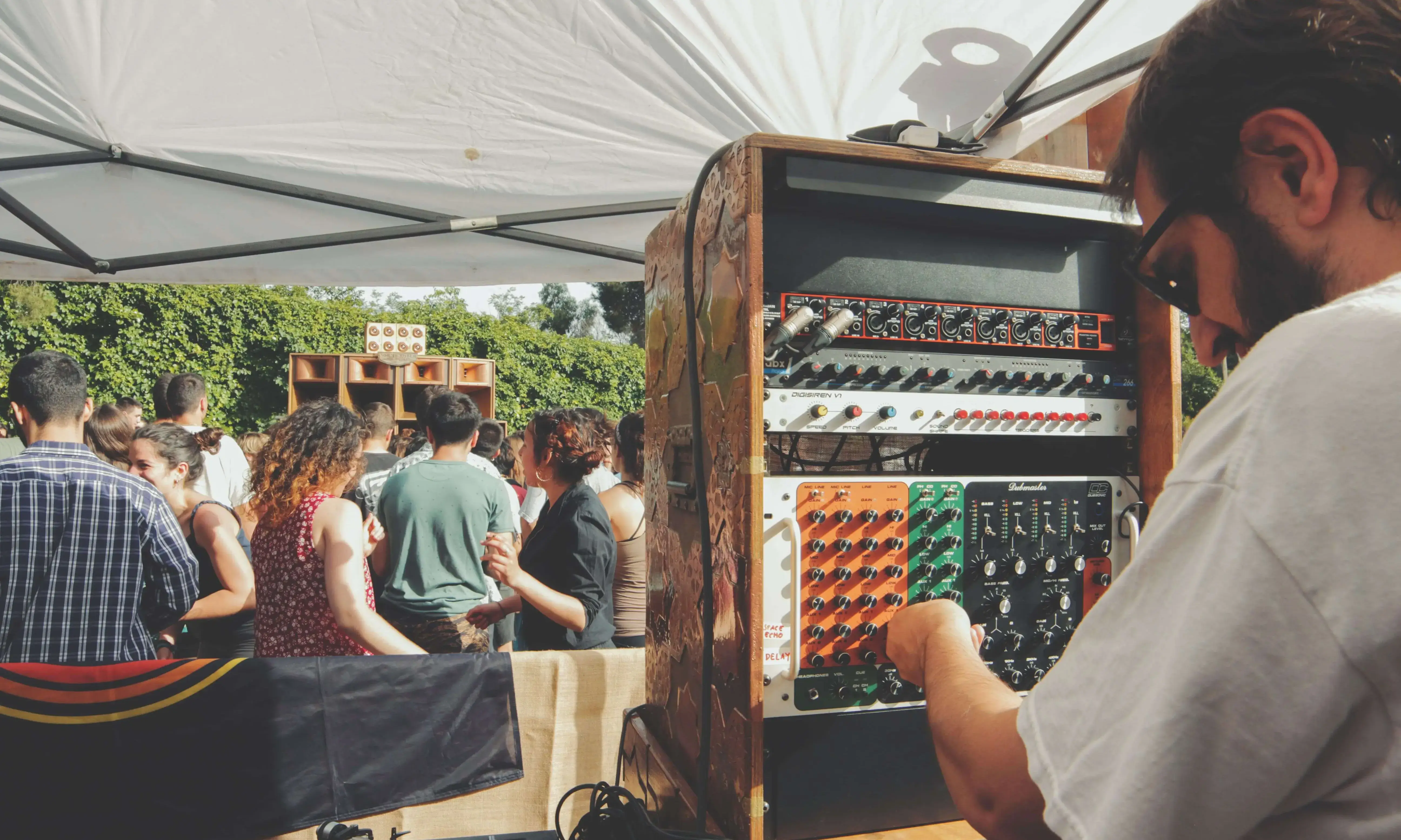 Un DJ toca en una carpa mentre un grup de persones ballen la seva música.