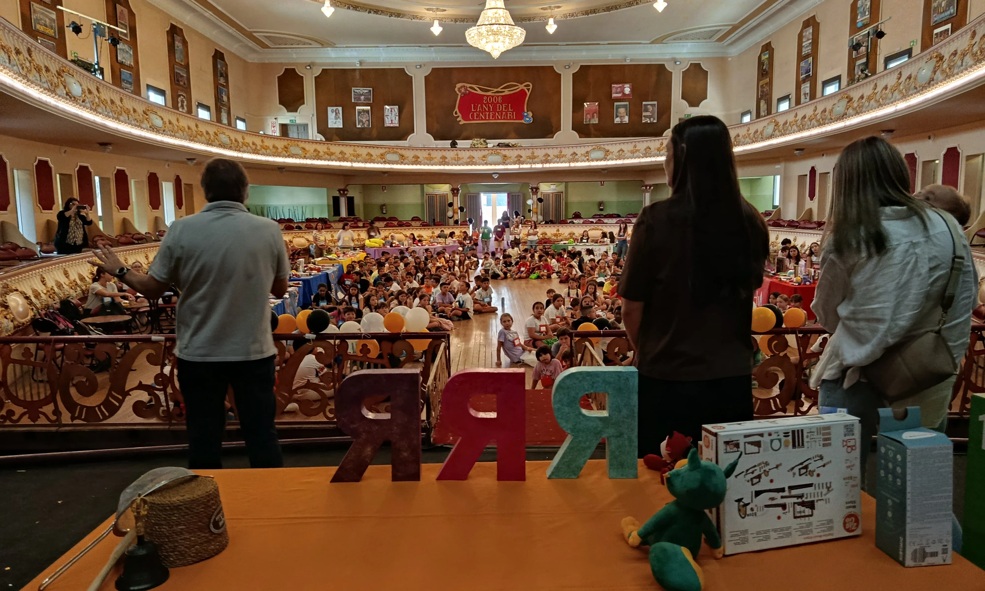 Infants en un teatre atenent a una sessió de reparació de joguines.