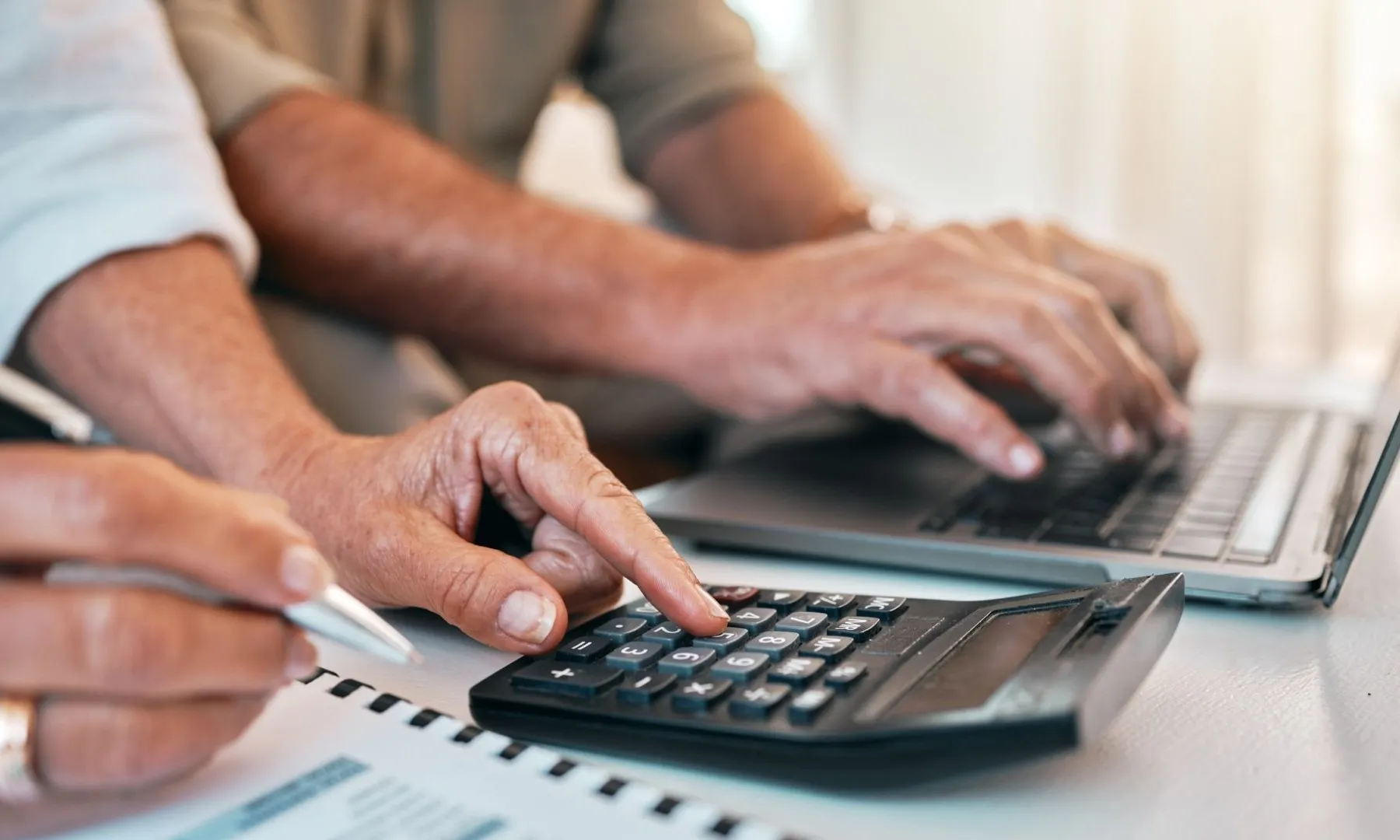 Dues persones utilitzant una calculadora i un ordinador portàtil per revisar documents econòmics.