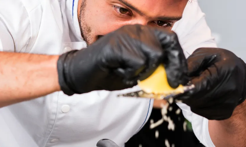cuiner amb guants negres manipulant un aliment