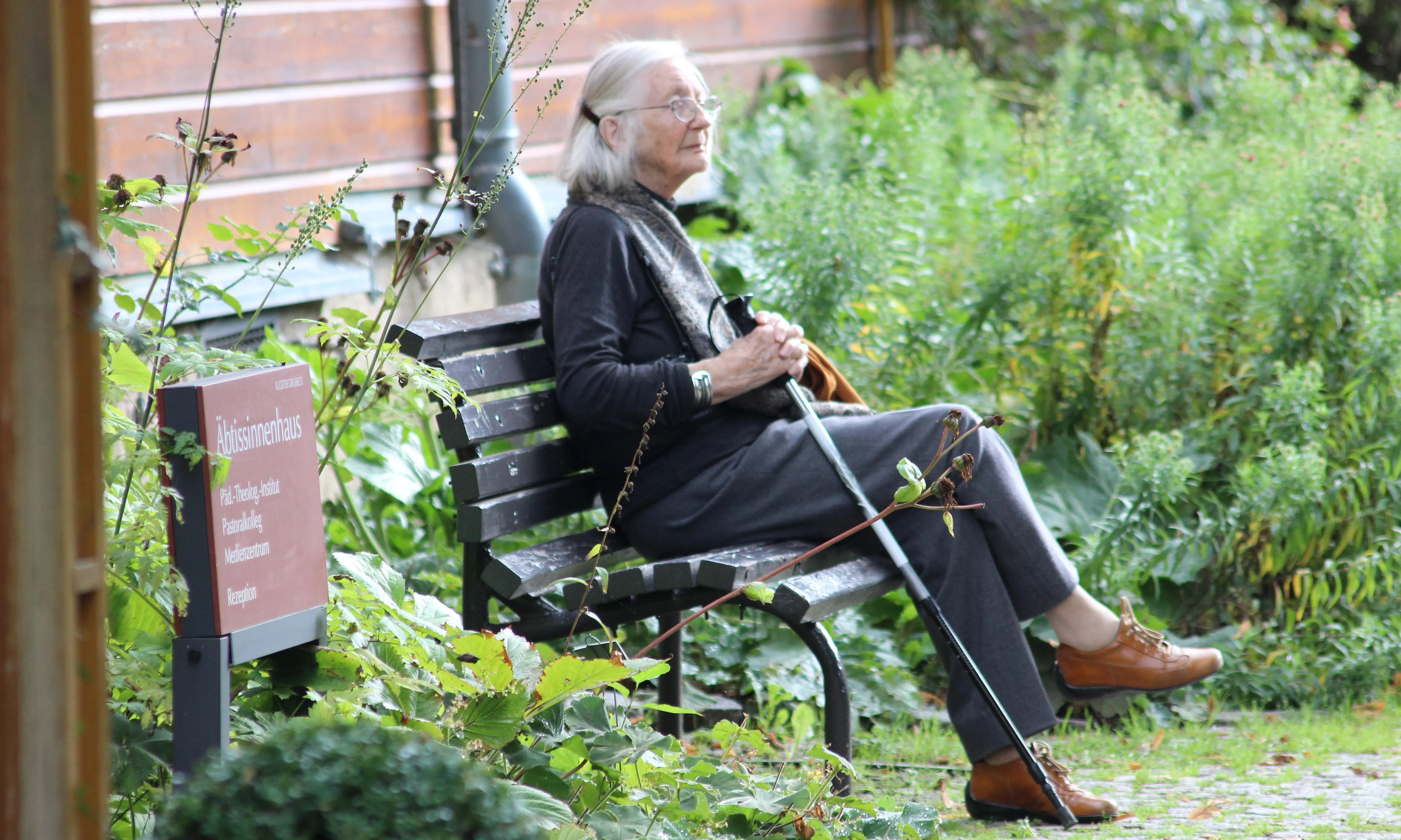 Persona gran asseguda en un banc