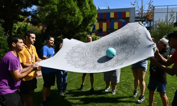 Persones que juguen amb una manta i una pilota. 
