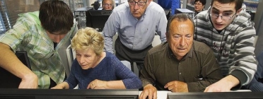 Voluntaris ensenyant a fer servir l'ordinador a gent gran. Font: ara.cat