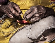 Una treballadora cosint sabates a casa seva. Font: Campanya Roba Neta Font: 