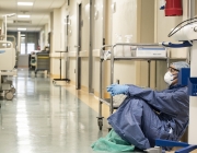 Una infermera amb un EPI jau al terra en un hospital. Font: Wikimedia Commons