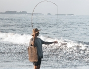 Noia pescant a la platja. Font: Pexels - ROMAN ODINTSOV