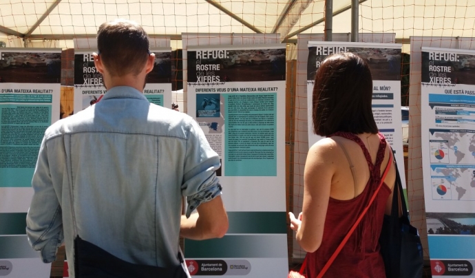Dues persones presencien una exposició fotogràfica sobre persones refugiades.  Font: Ajuntament de Barcelona
