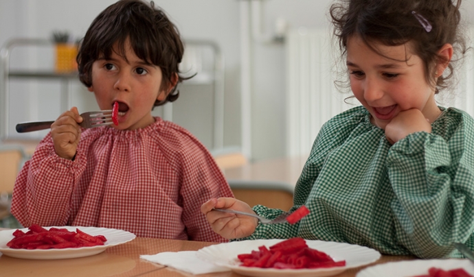 Infants menjant macarrons amb salsa de remolatxa - Menjadors escolars ecològics Font: Associació menjadors ecològics (Facebook)
