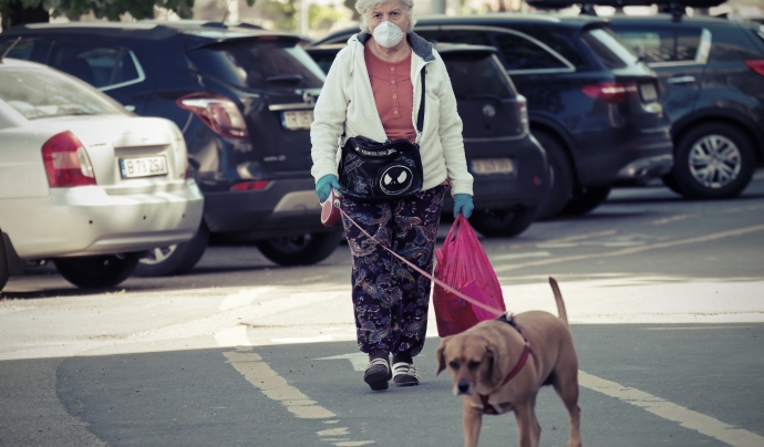 Una dona gran passeja al seu gos protegida amb una mascareta. Font: Pexels