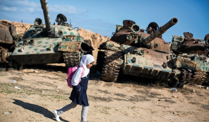 Amal al Torchani, una nena d'11 anys que en la imatge camina davant dos tancs aturats. És el camí que ha de fer per anar a l'escola, a Misrata, Líbia (Font: flickr.com - Autor: Jordi Bernabeu Farrús)
