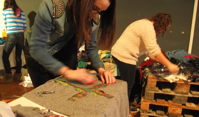 Una noia redissenyant un jersei durant el taller de reciclatge de roba a la UAB. Font: 