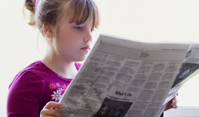 Fotografia d'una nena llegint un diari Font: 