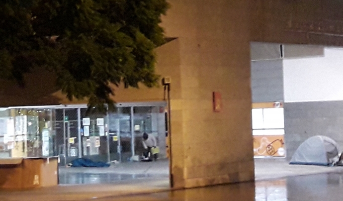 Persones dormint en una plaça de l'Eixample, a Barcelona, una nit de pluja. Font: Sònia Pau