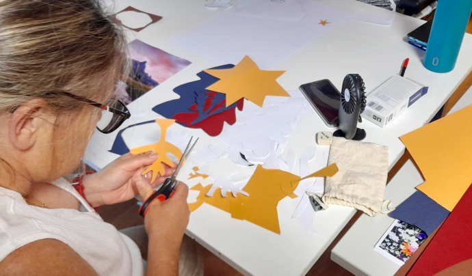 Una treballadora de l'ADFOCET retallant cartulines de colors al taller de superpoders. Font: ADFO (Associació Diversitat Funcional d'Osona)