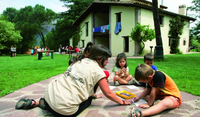 Fotografia de nens jugant a terra, davant una casa de colònies Font: 