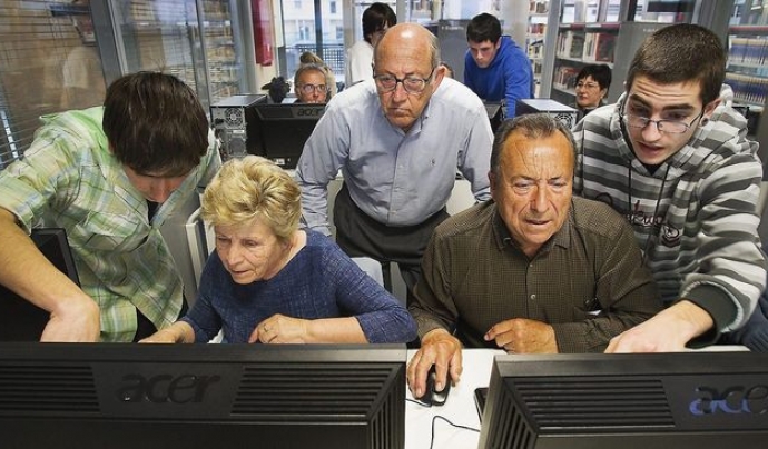 Voluntaris ensenyant a fer servir l'ordinador a gent gran. Font: ara.cat